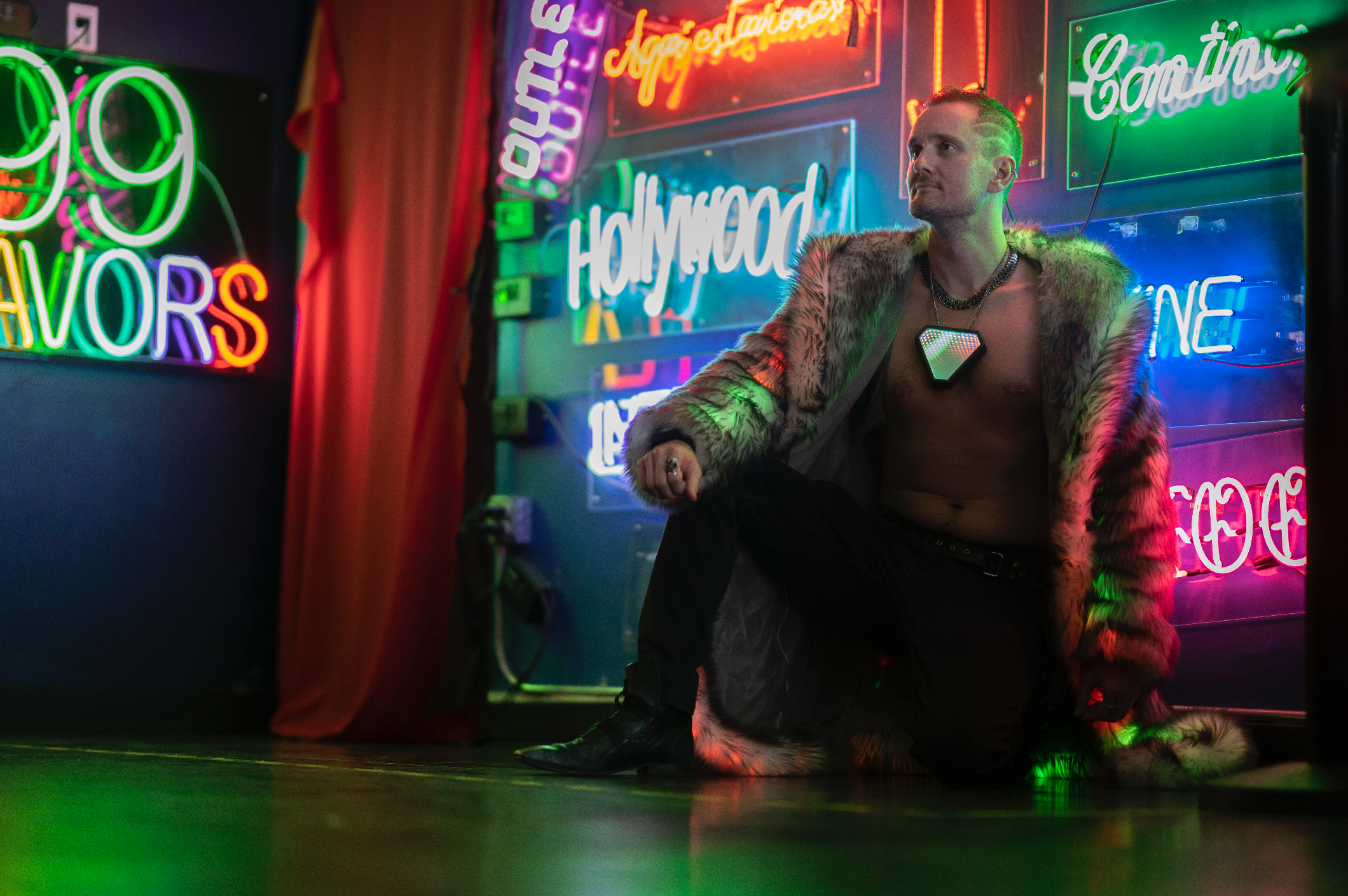Portal's founder wearing the 'Prisma' infinity mirror necklace, posed in front of colorful neon signs