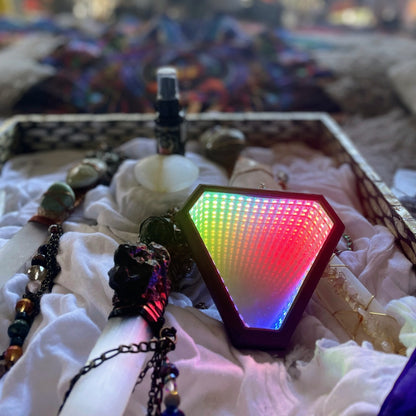 Portal's 'Prisma' infinity mirror necklace displayed on a tray with crystals