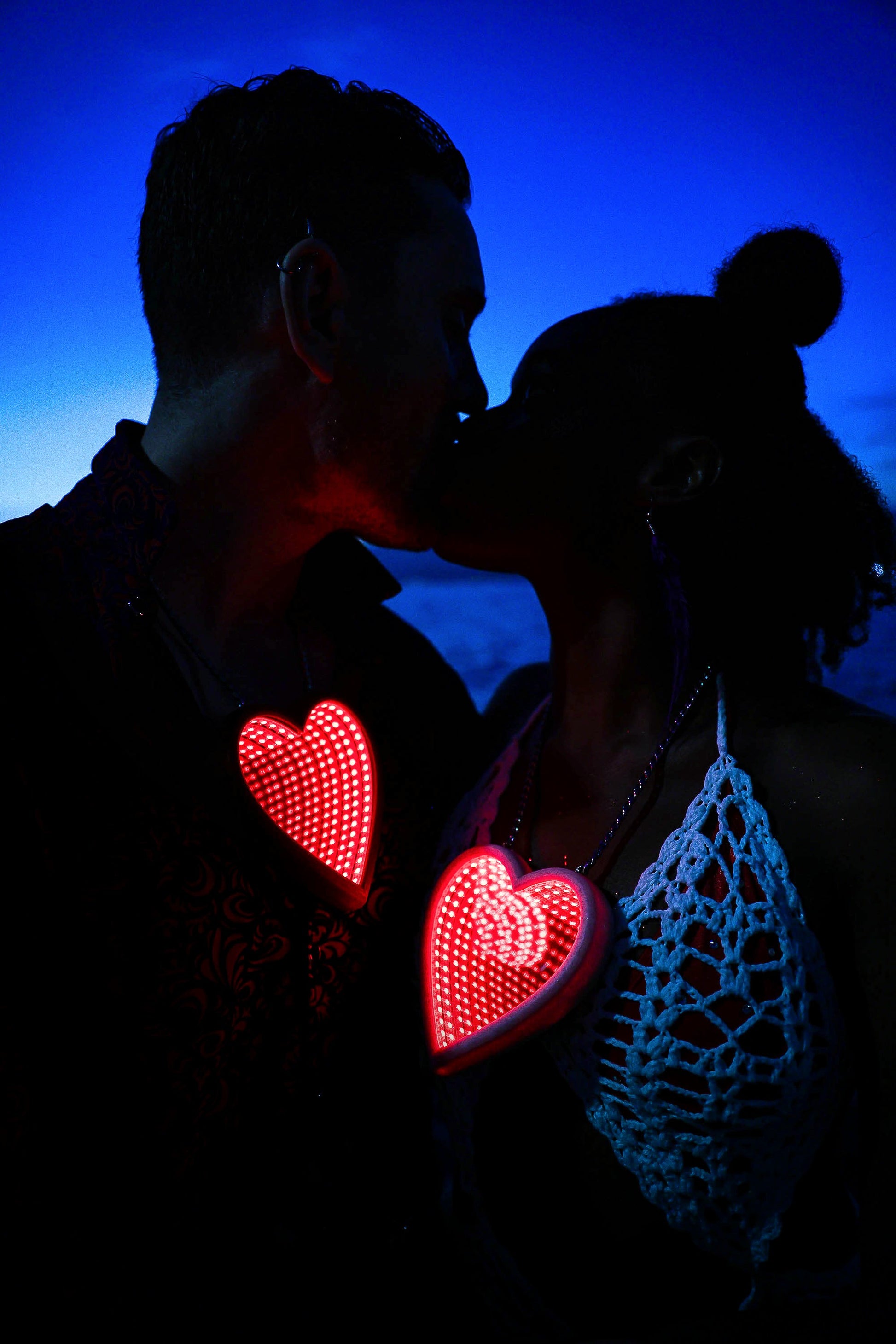 Silhouette of 2 lovers kissing as they wear Portal's heart shaped infinity mirror necklace